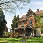 brown brick house near green grass field and trees during daytime