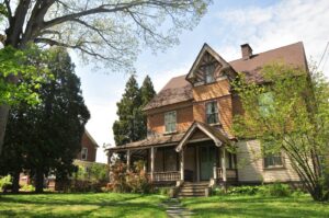 brown brick house near green grass field and trees during daytime